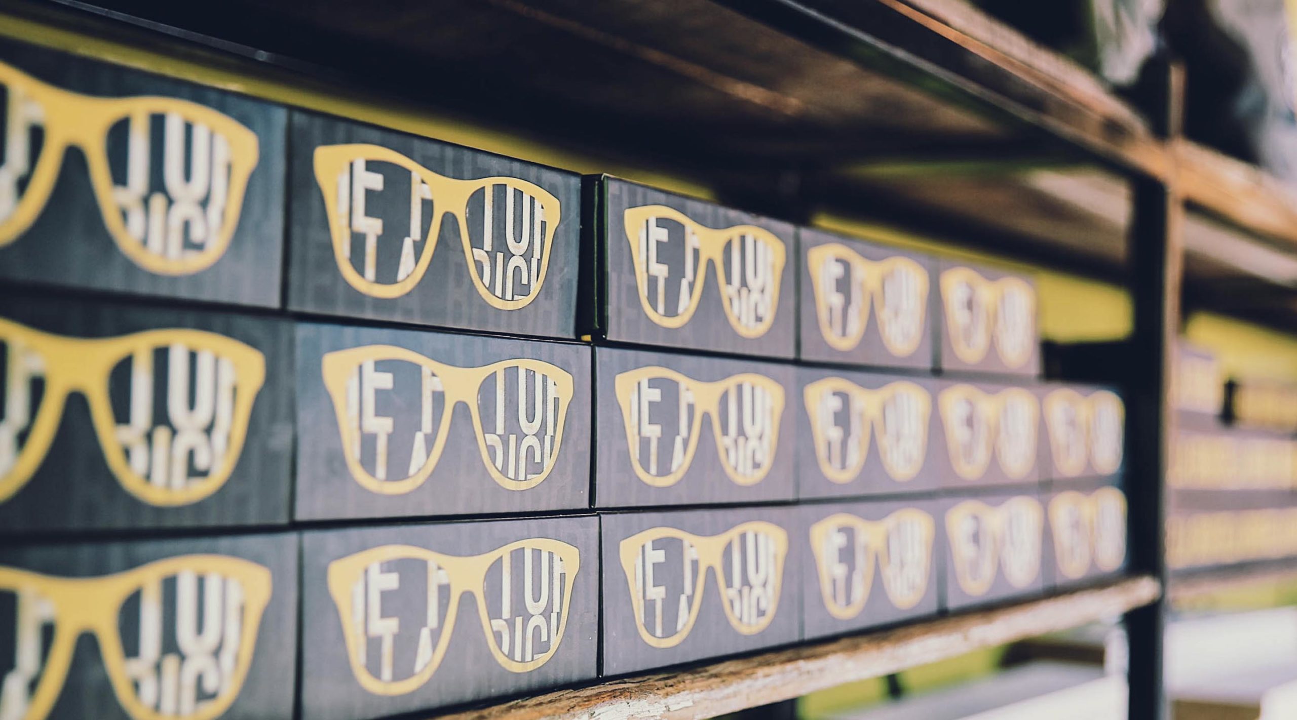 Shelf with rows of black boxes with yellow sunglasses printed on them